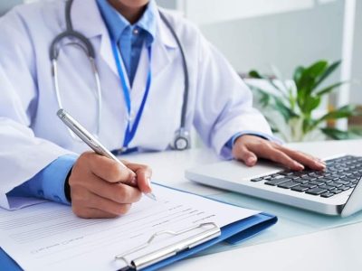Doctor checking information in computer program before filling medical card
